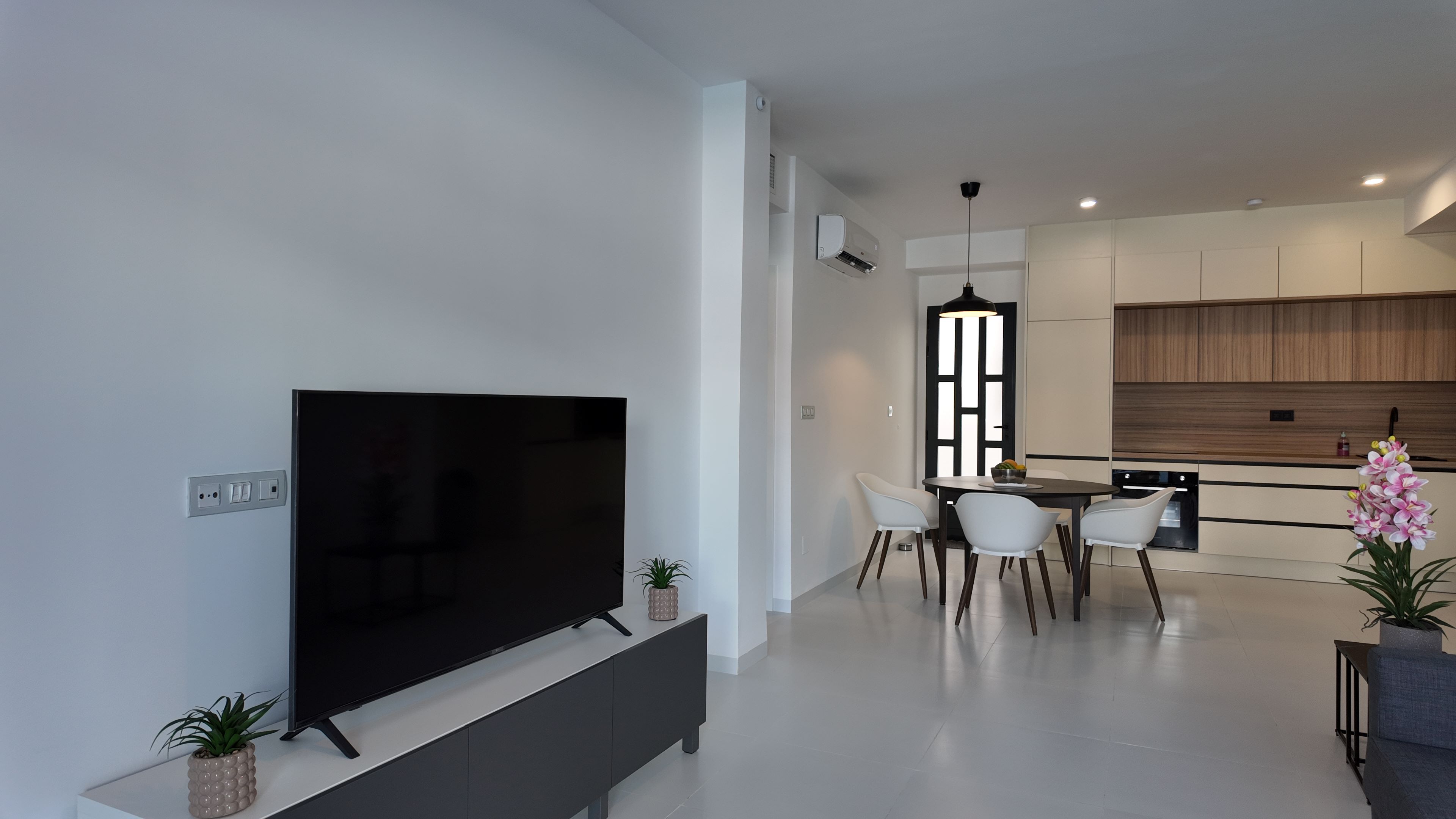 Woonkamer met televisie, eethoek en open keuken